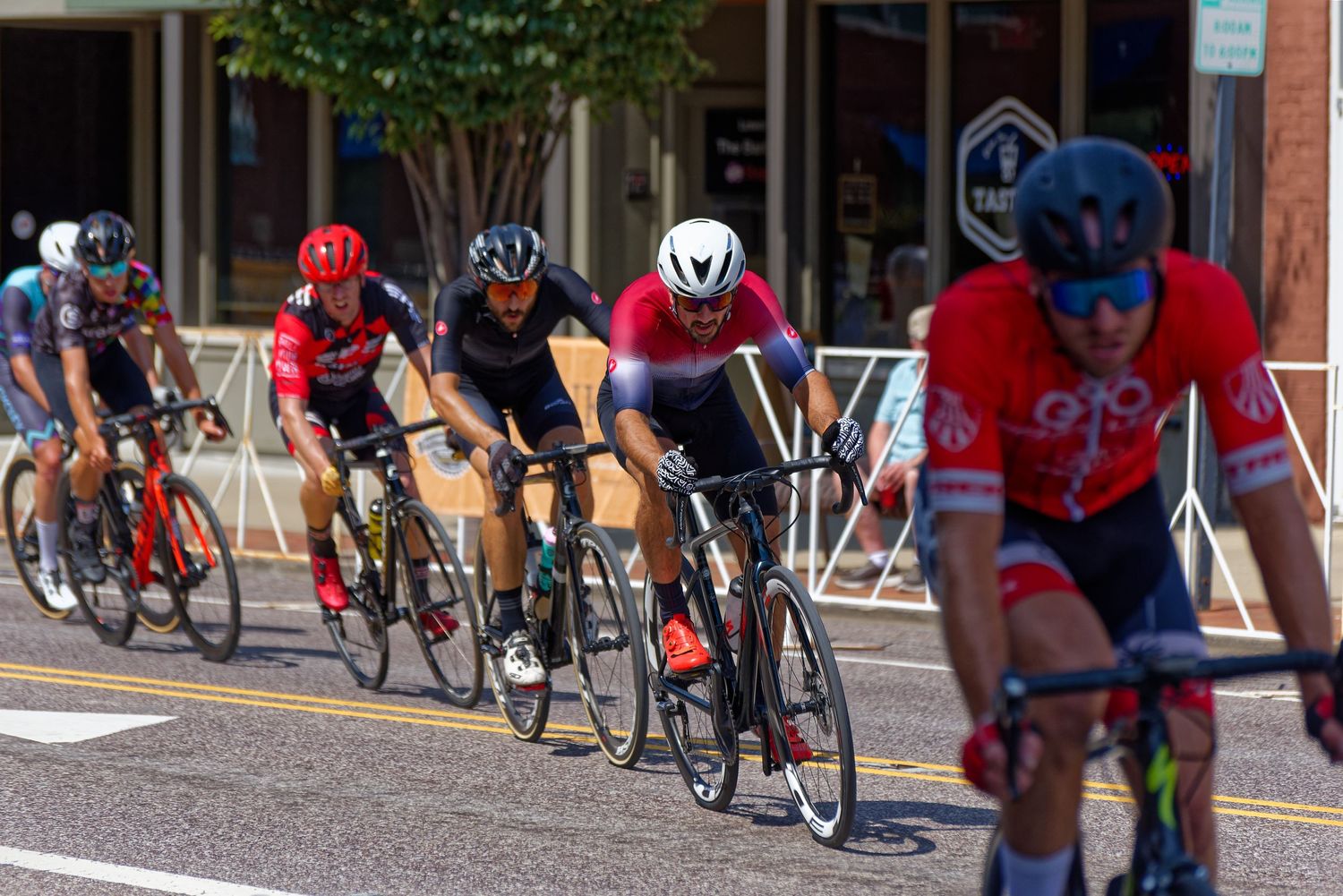 Group of cyclists racing in close formation on city street during competition.