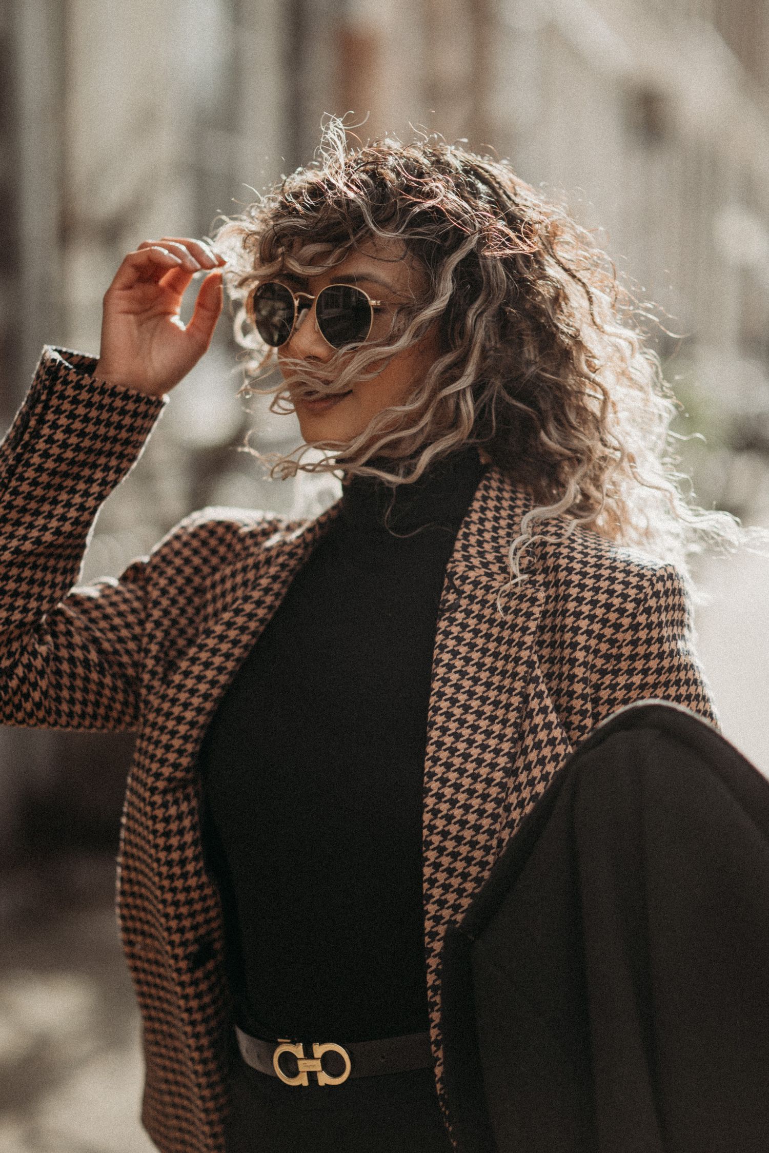 Stylish portrait on the streets of Amsterdam: a curly-haired woman wearing sunglasses.