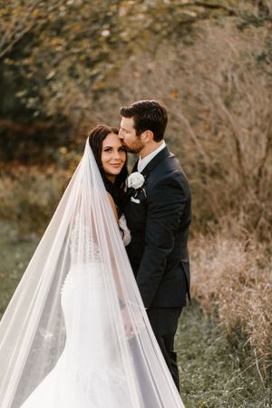 Romantic wedding portrait of couple embracing outdoors in autumn setting.