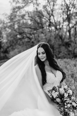 Black and white bridal portrait with flowing veil and floral bouquet.