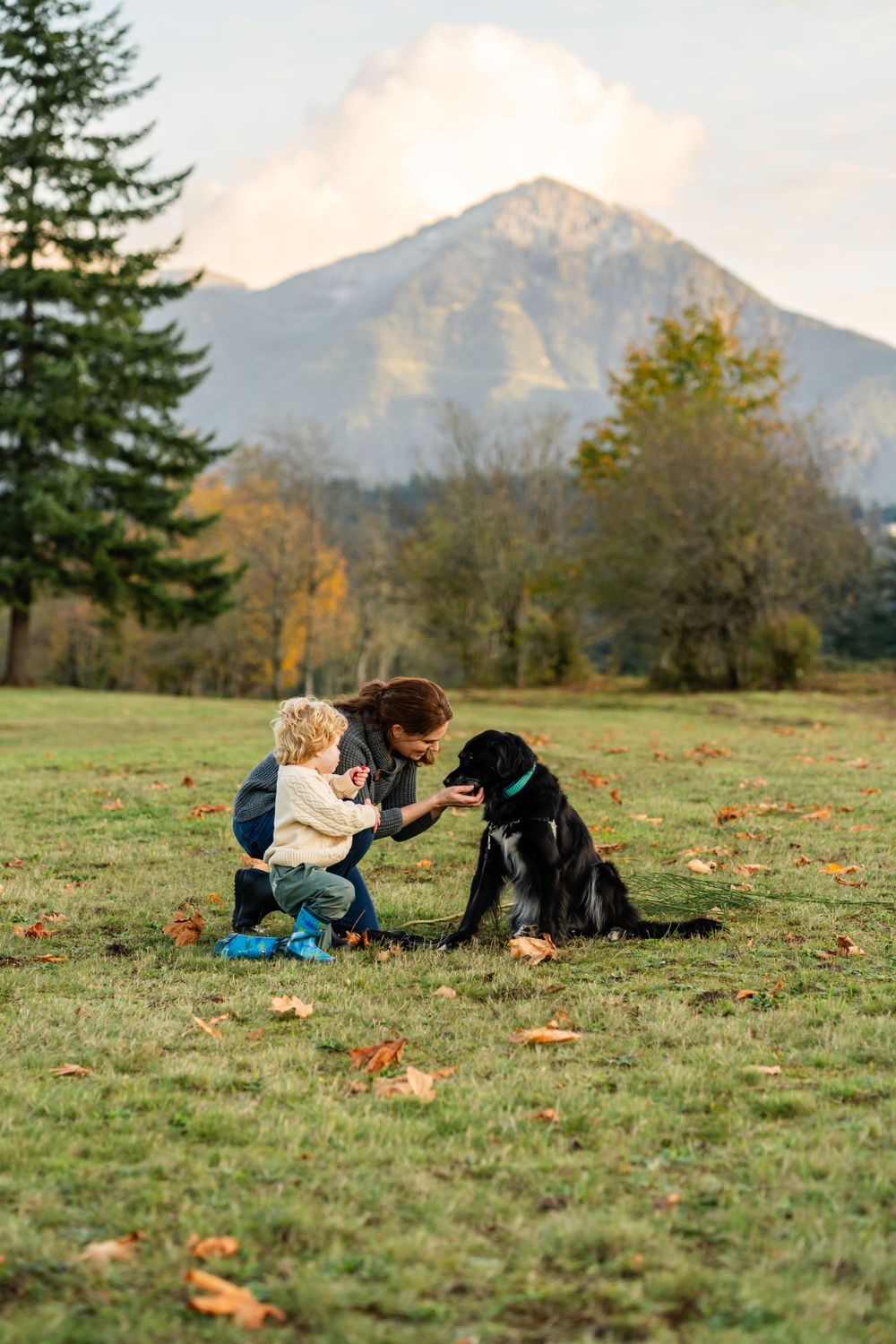 Mother and son playing with dog with mountain backdrop in North Bend.