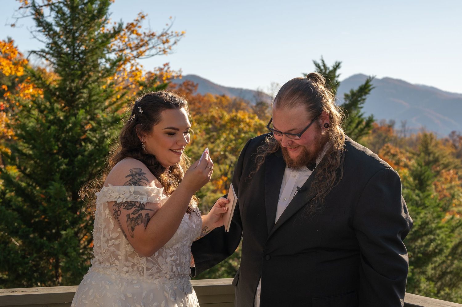 A romantic wedding moment captured on a deck overlooking autumn mountains in golden sunlight.