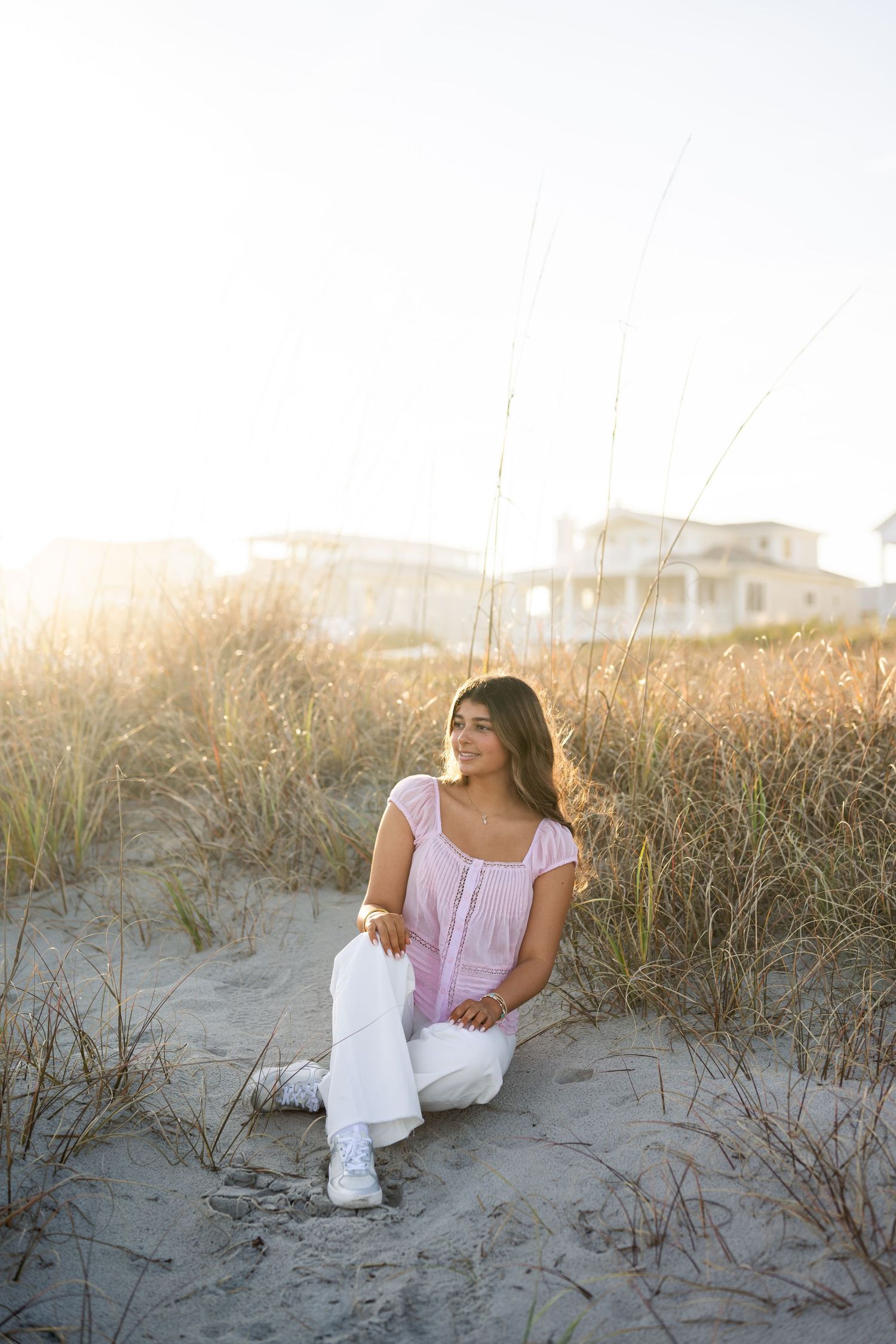 Portrait of young woman with flowing hair in black shirt against golden sunlight.