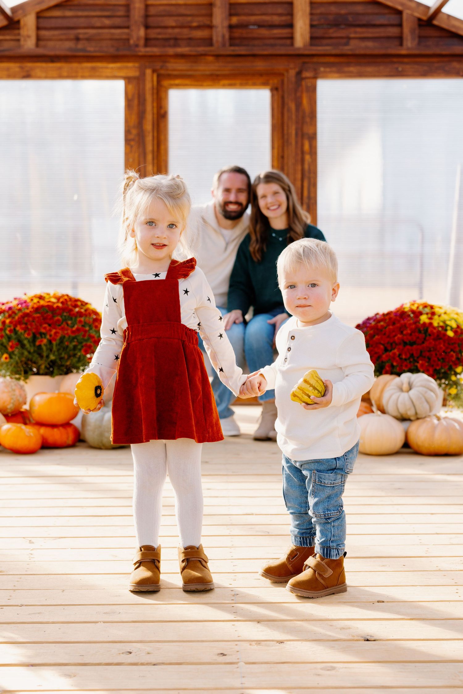 Fall family photo with pumpkins and mums on wooden deck.