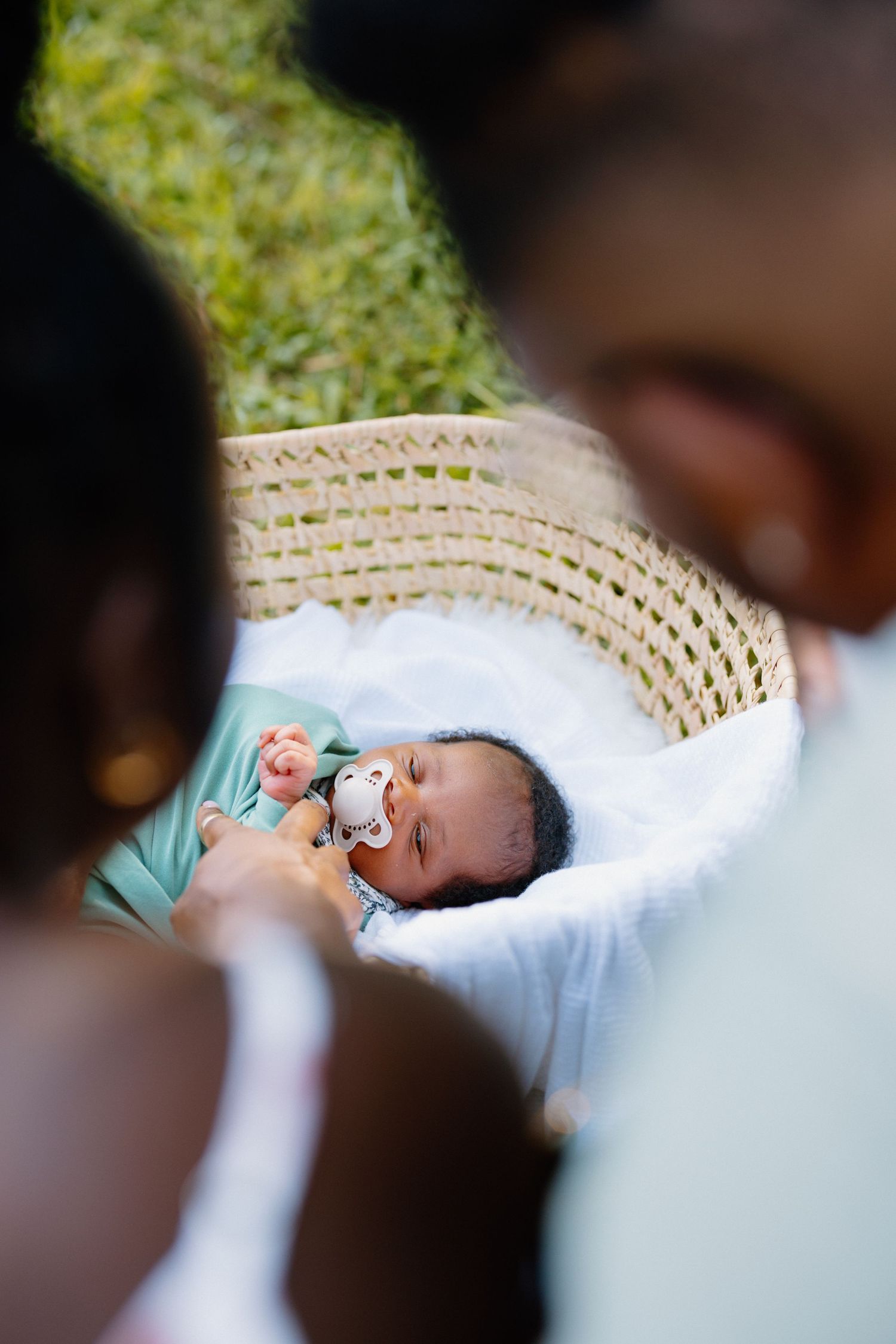 Newborn baby sleeping peacefully in white bassinet with pacifier.