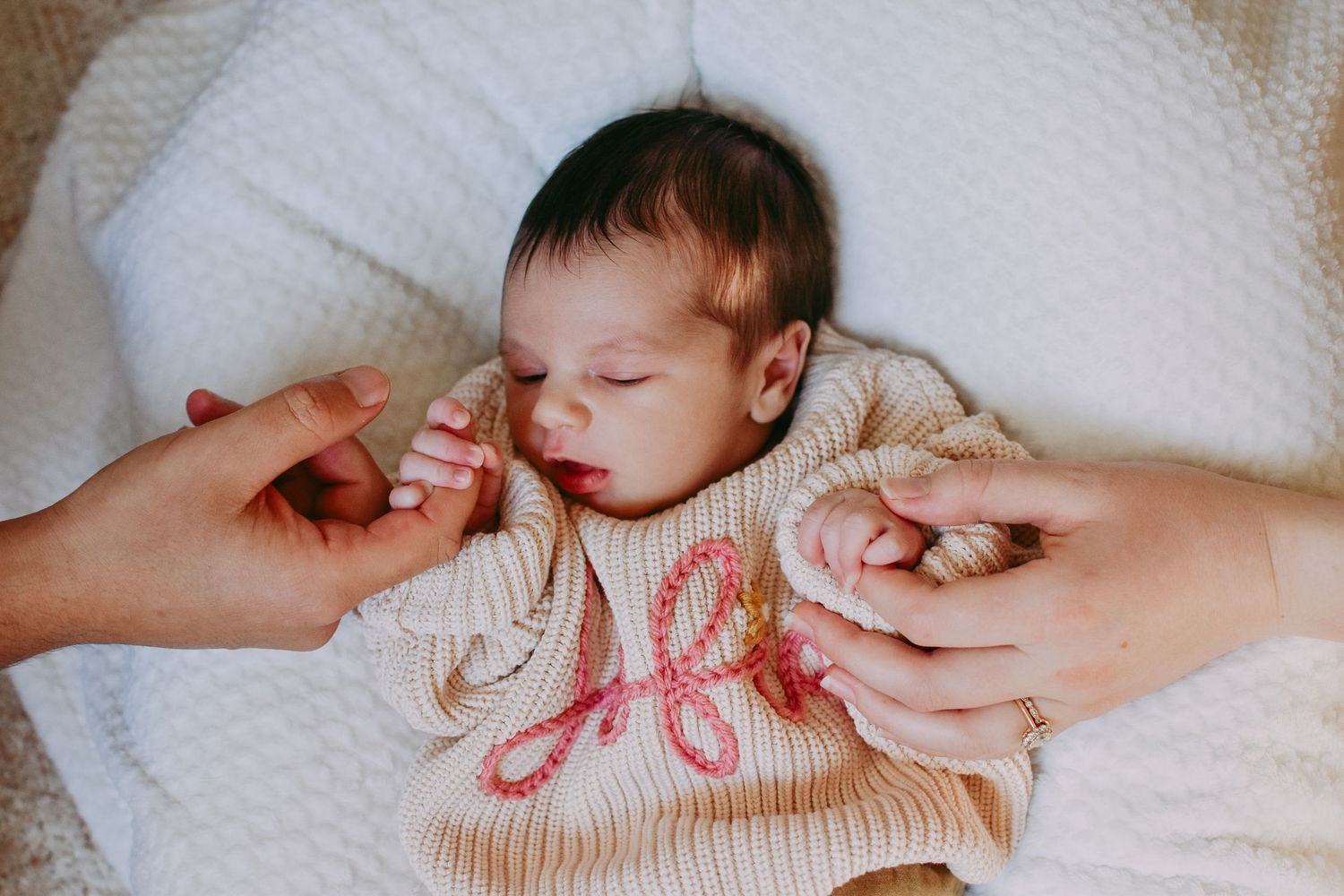 Close-up of sleeping infant wearing cream colored sweater.