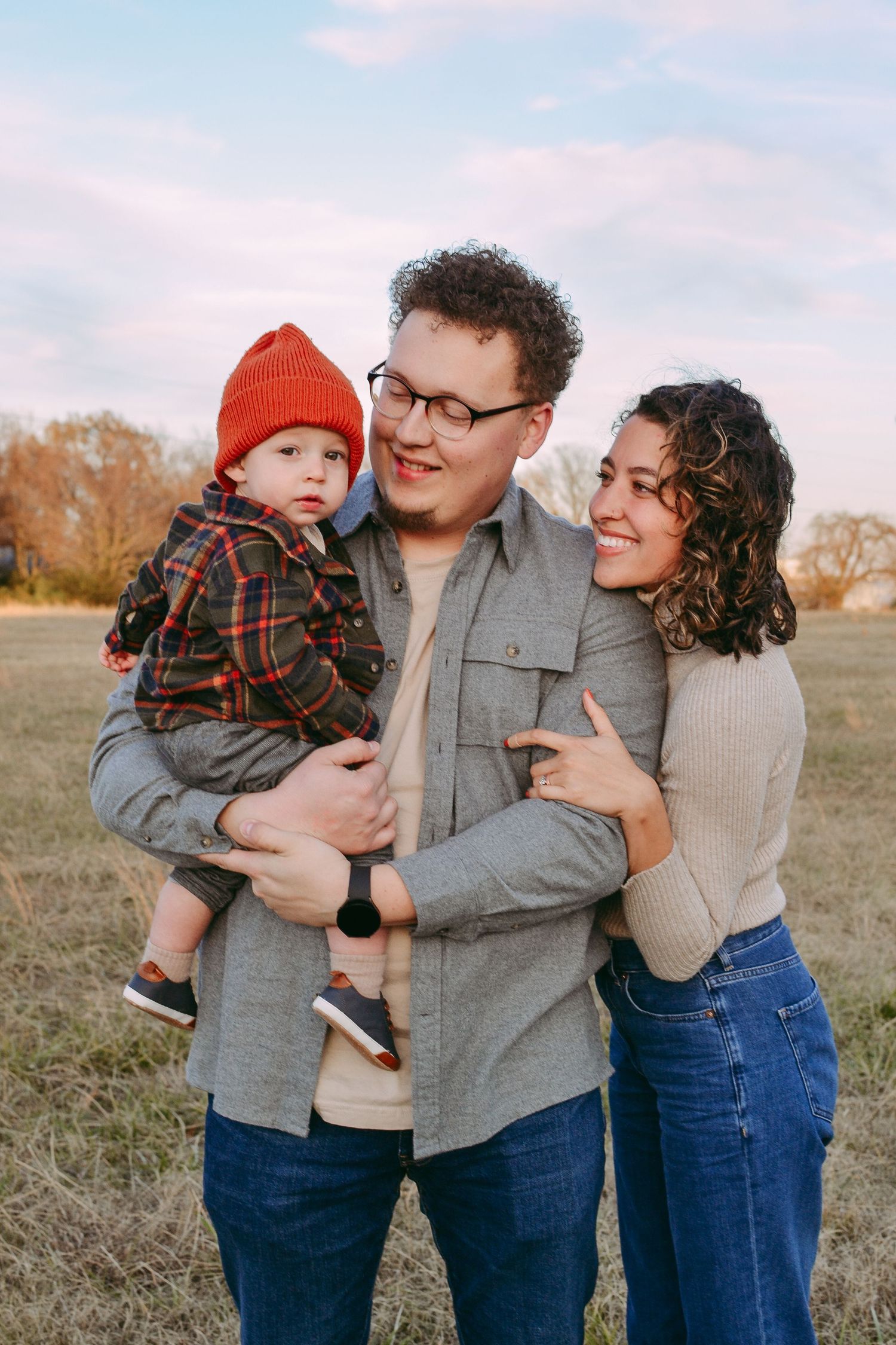 Family portrait outdoors during sunset in casual attire.