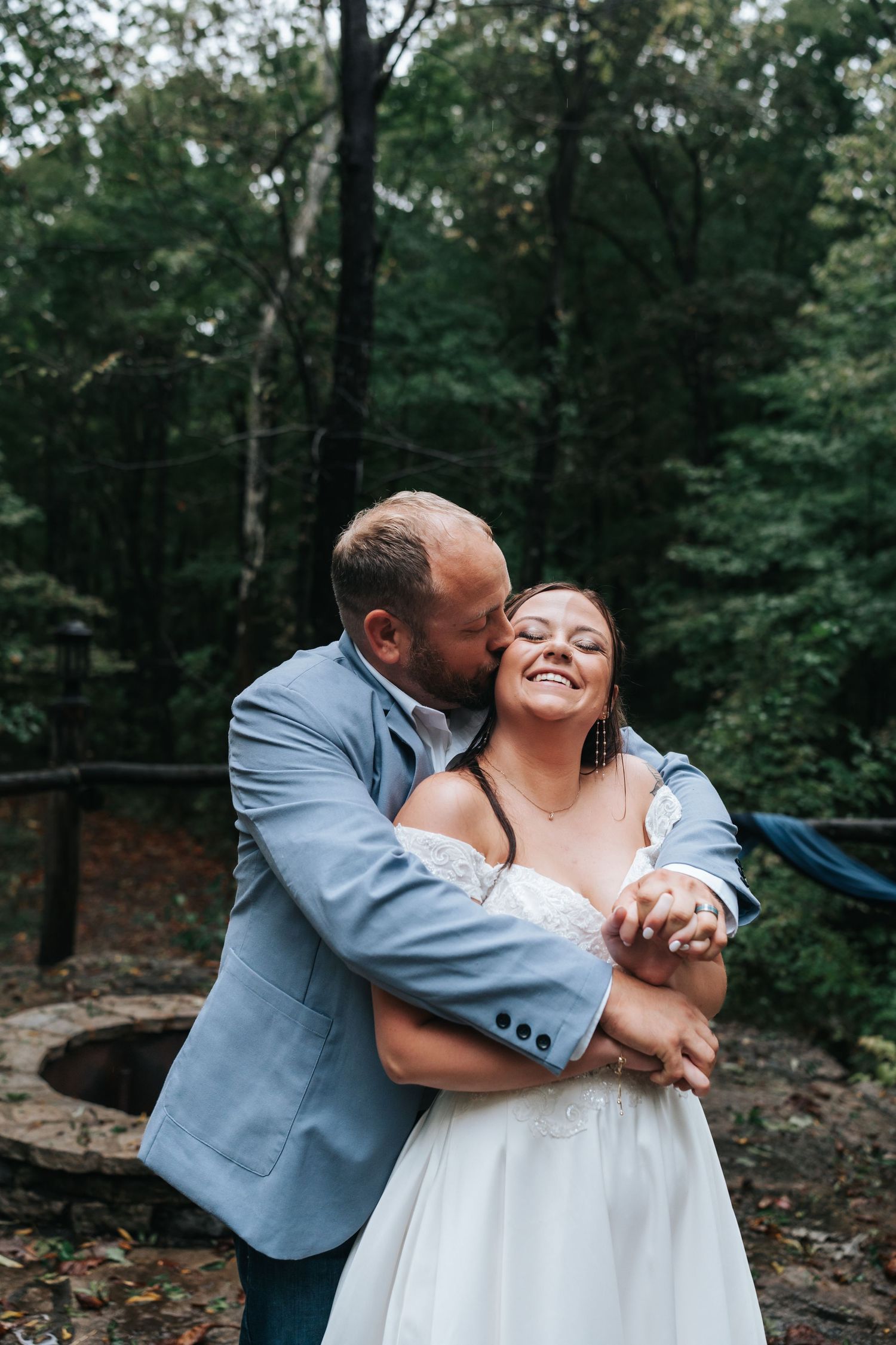 Affectionate moment between newlyweds embracing in a wooded outdoor setting.