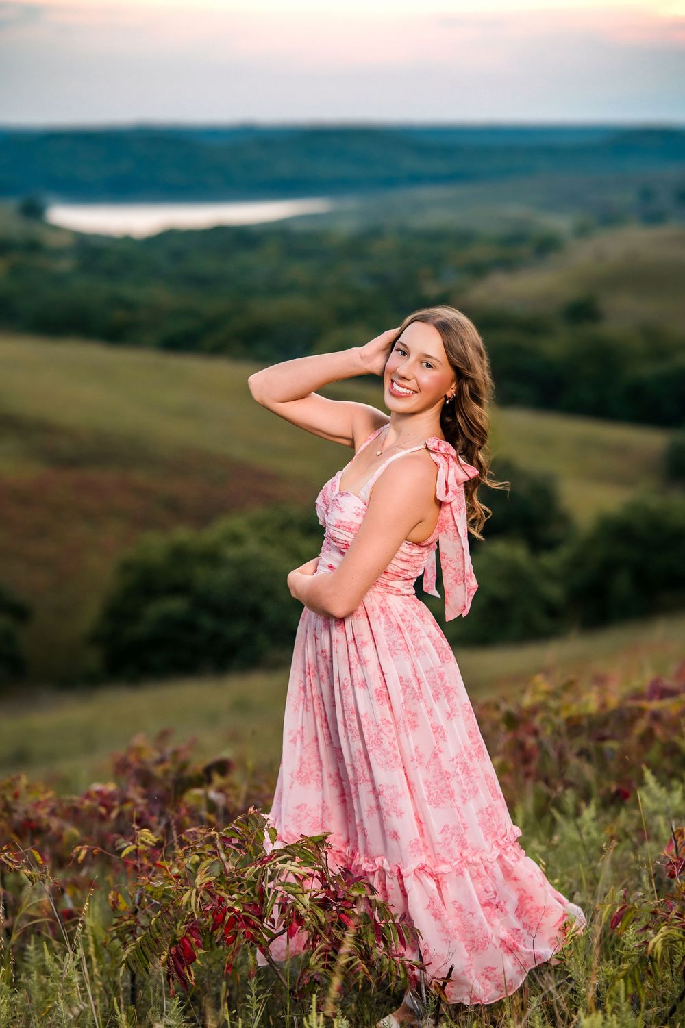 Pink floral sundress stands out against the natural landscape of wildflowers and rolling hills.