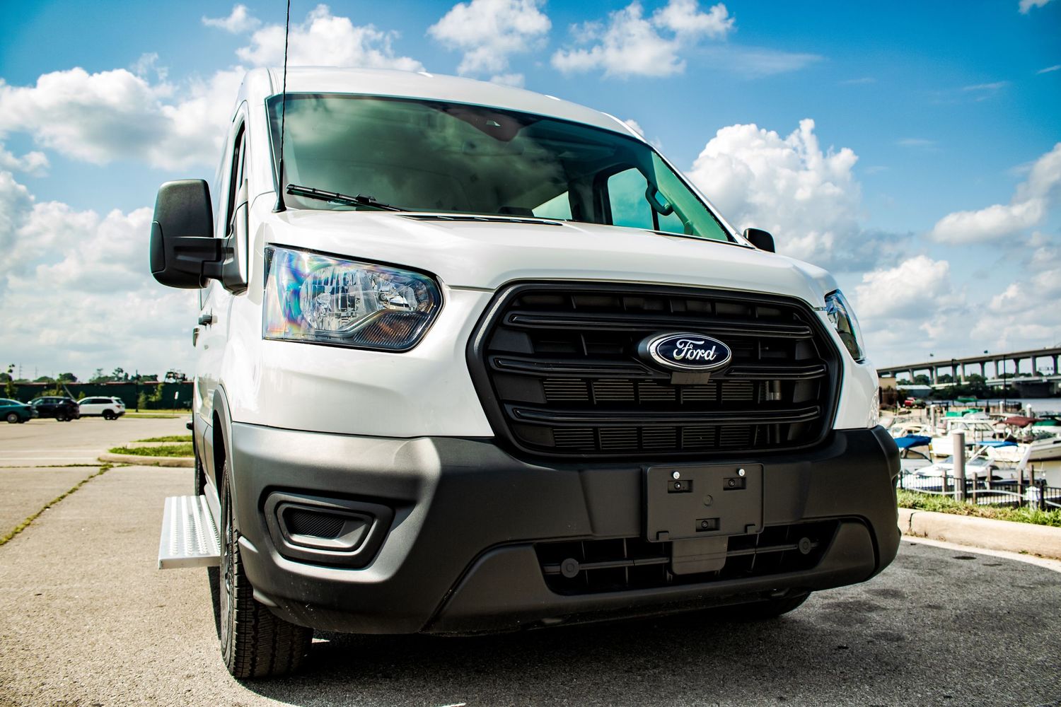 Front view of a white Ford Transit van with black grille parked on concrete.