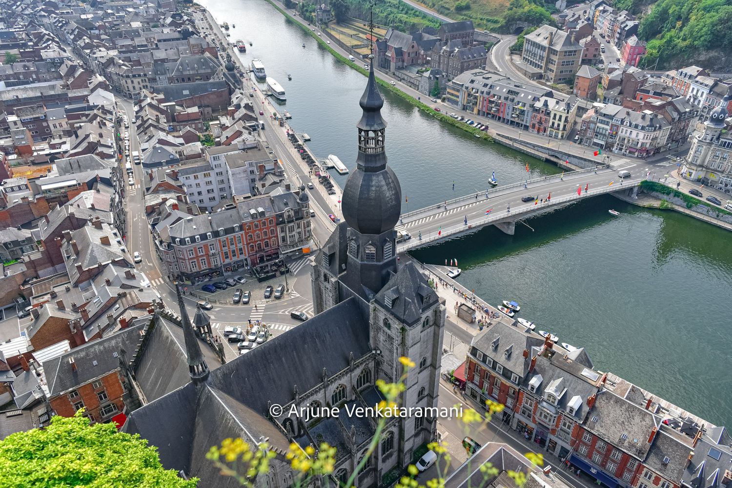 Aerial view of a European city with a domed church, river bridge, and dense urban architecture along the waterfront.