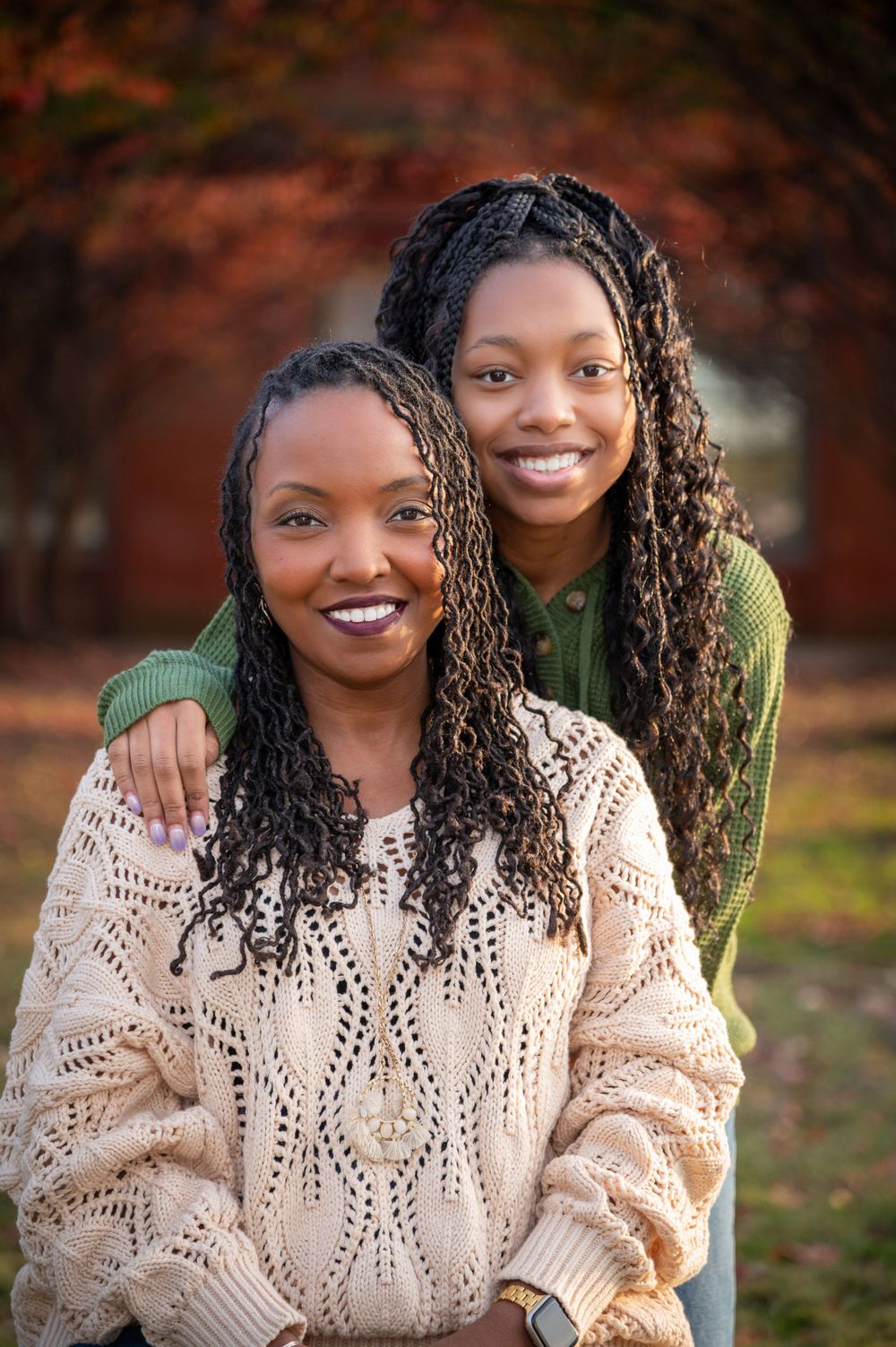 A fall portrait session with autumn foliage in the background.