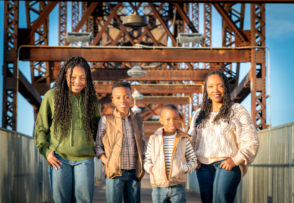 A group of people posing together against an industrial metal background.