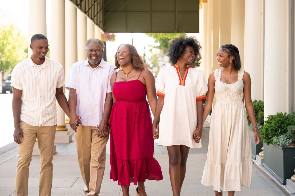 Group photo of people wearing coordinated outfits in white and red standing in front of columns.