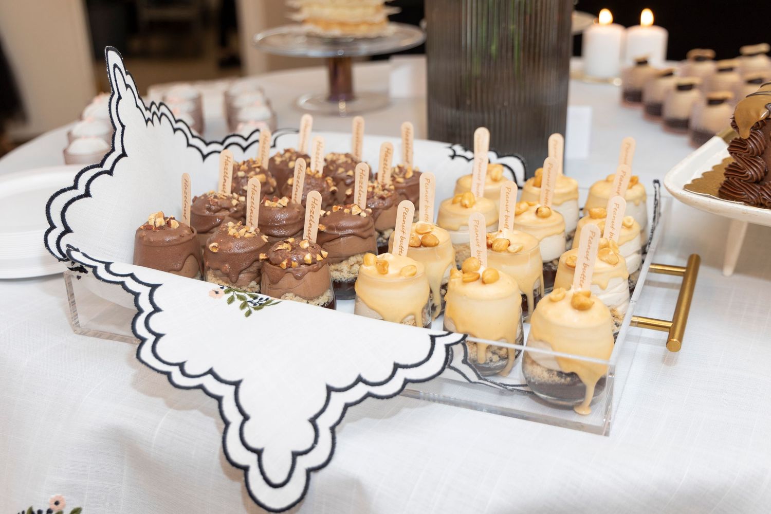 Dessert display featuring mini cakes with candles on decorative serving platter.