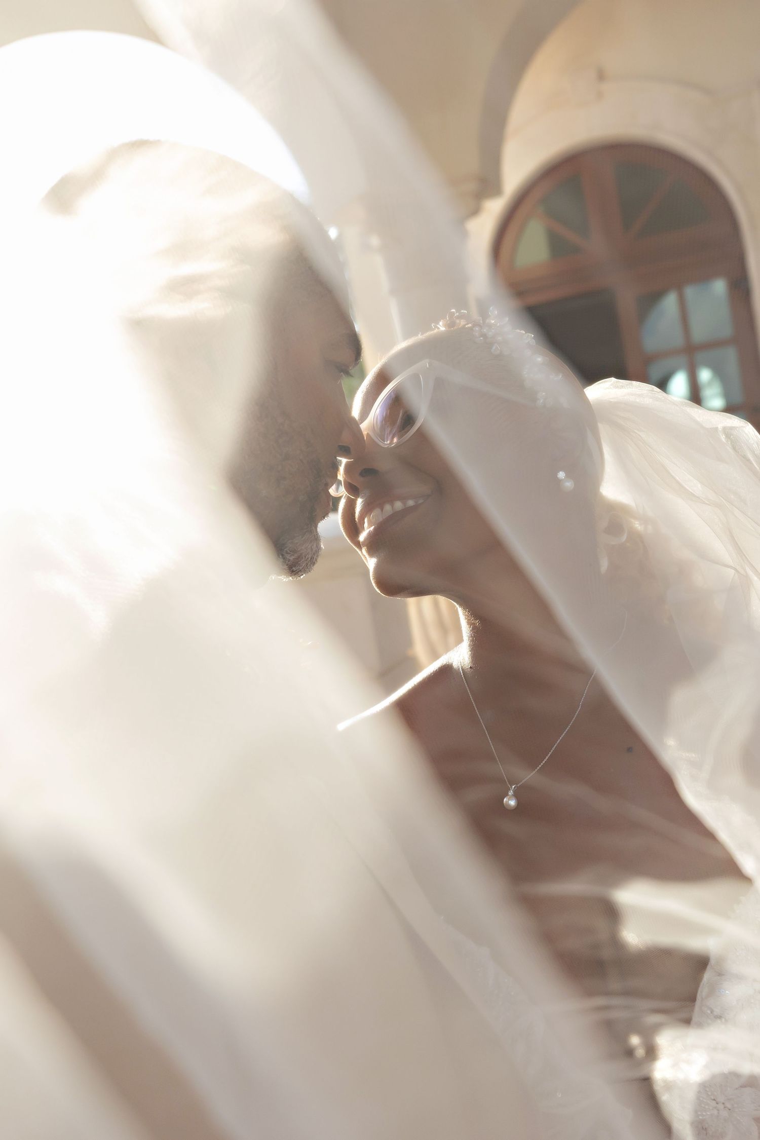 A couple shares an intimate moment on their wedding day against a white wall with dramatic shadow patterns at Villa La Joya.