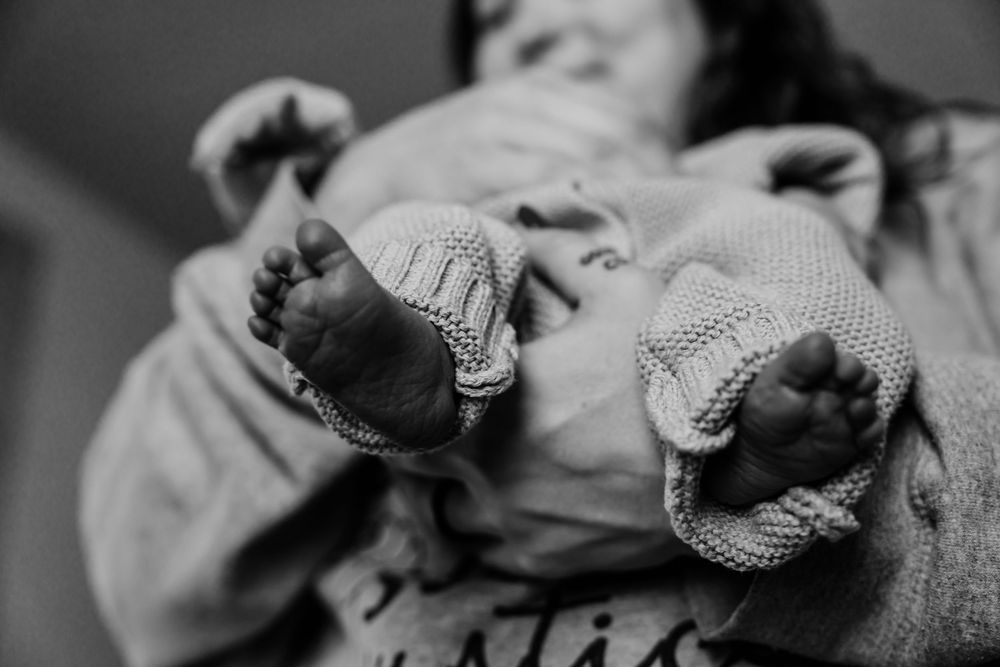 A series of black and white images showing a small newborn puppy in knitted clothing lying down.