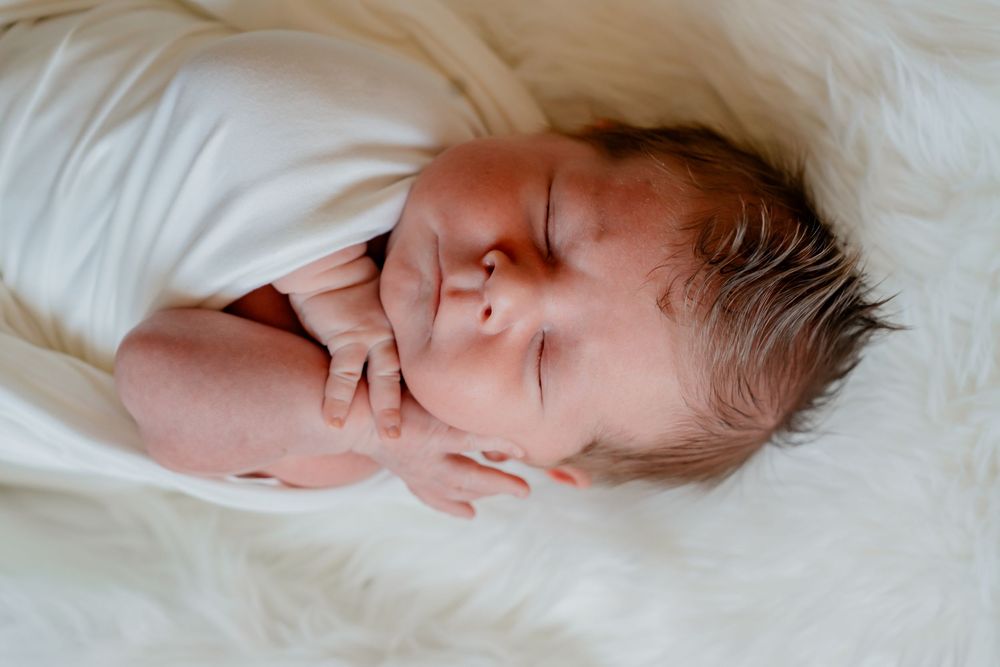A sleeping baby rests peacefully on white bedding in a series of connected images.