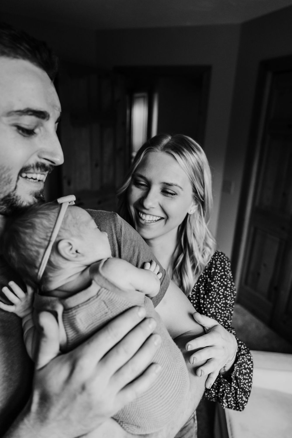 A black and white candid moment of happiness shared between parents and their infant.