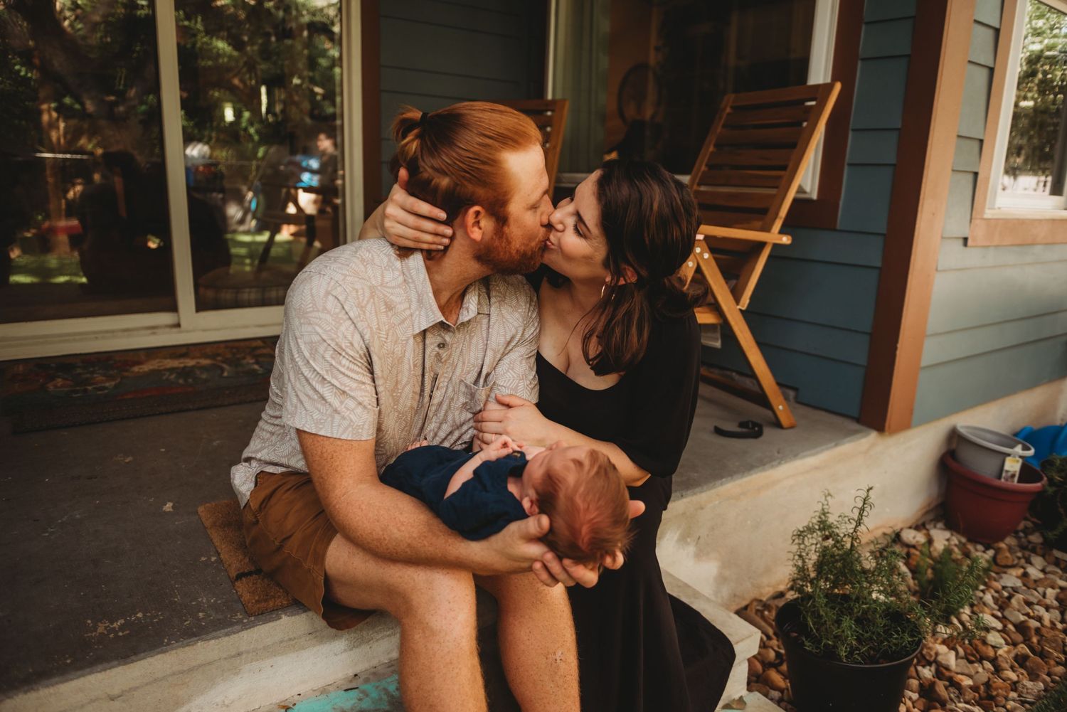 A couple shares an intimate moment while sitting together on their front porch during golden hour.