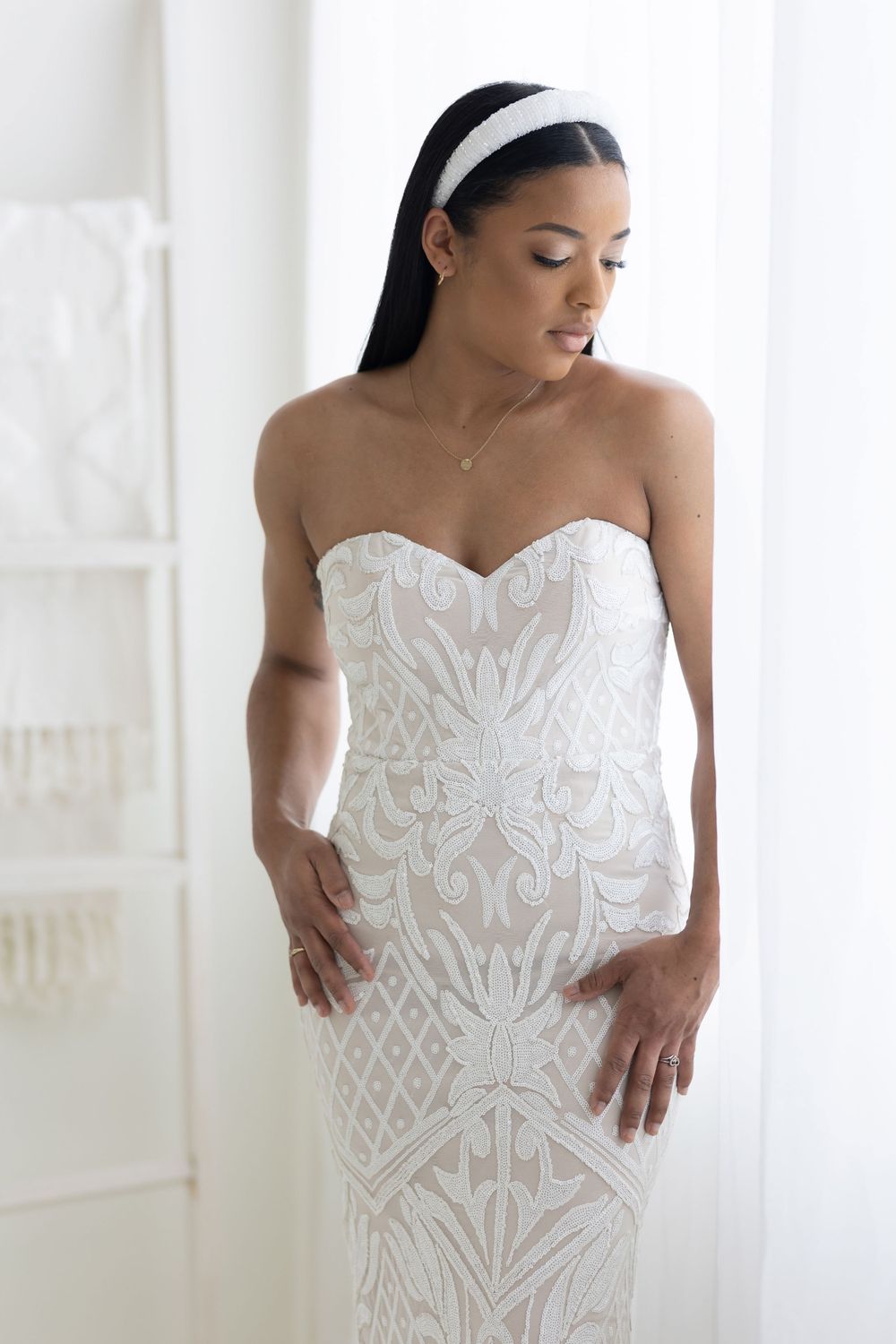 Bride in strapless white lace wedding gown with sweetheart neckline looking down gracefully.