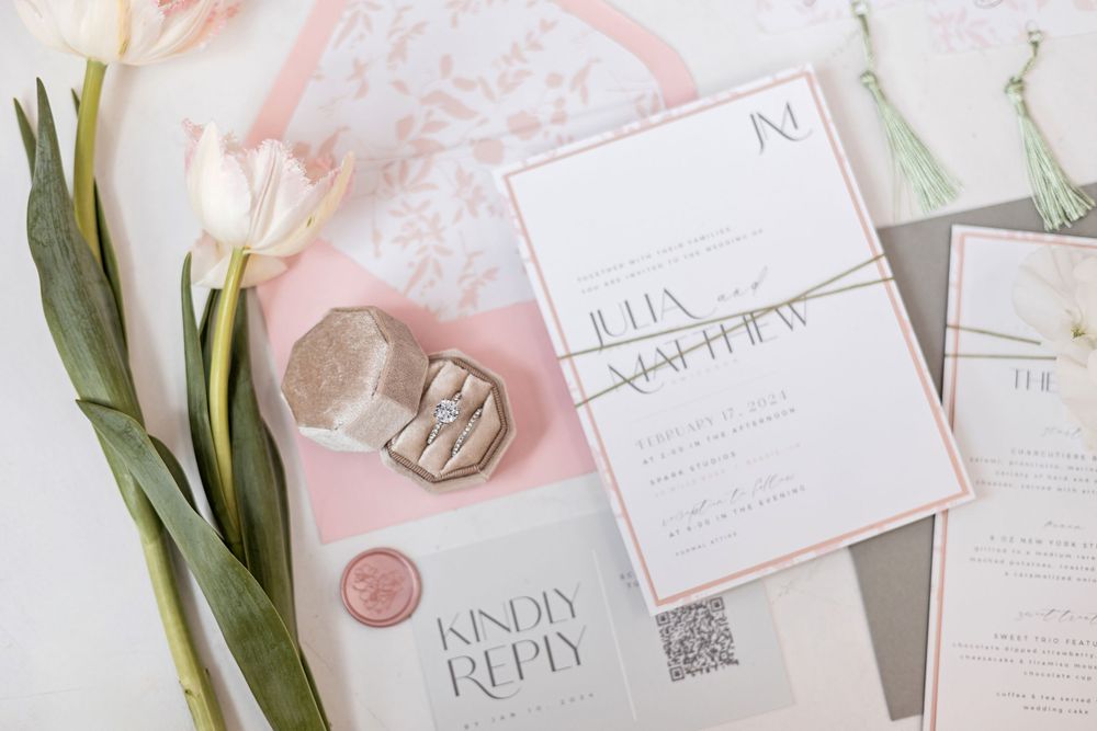 Elegant wedding invitation suite with pink and gray accents, wax seal, and floral details on white background.