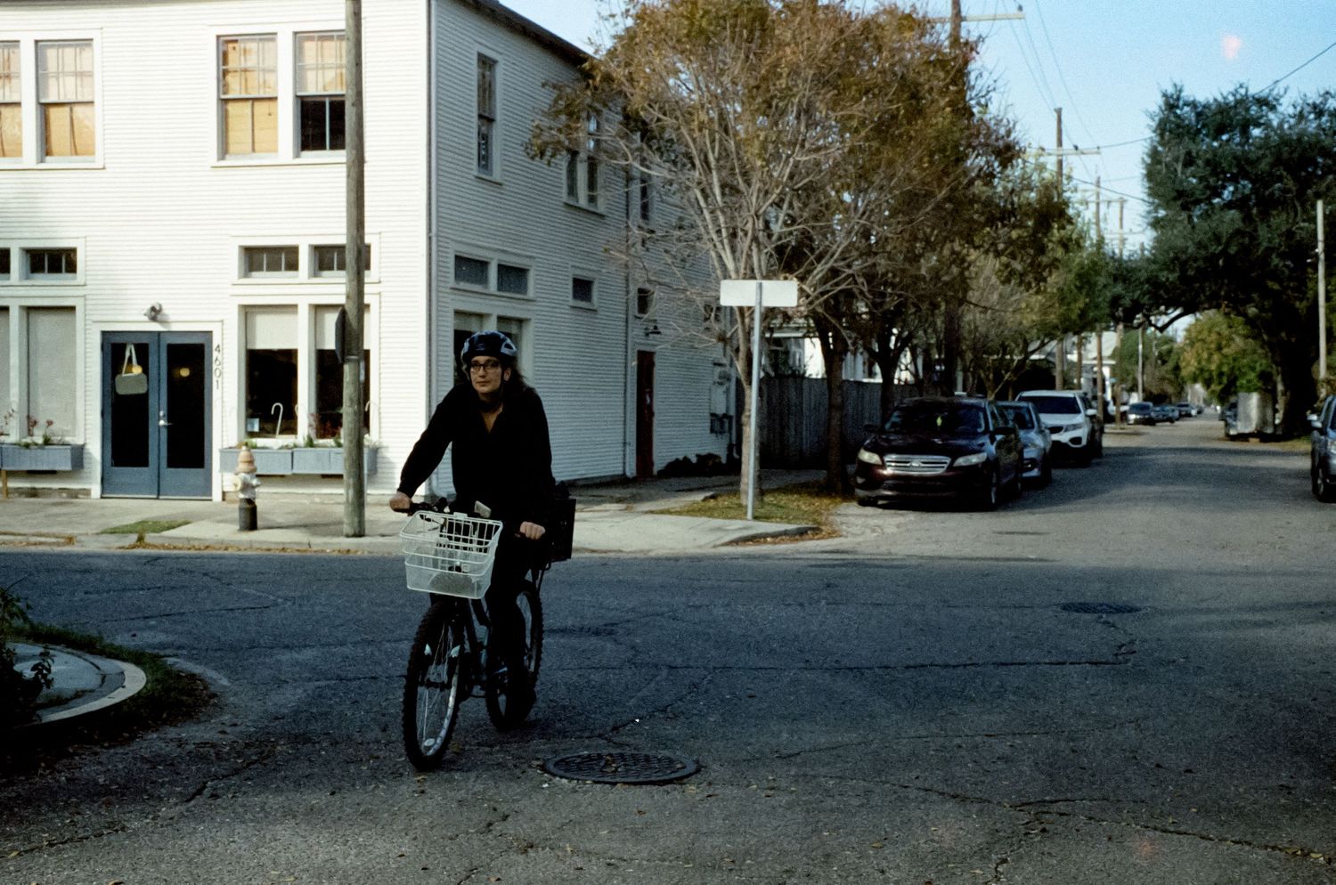 Cyclist riding through an urban intersection on a sunny day with white buildings in background.