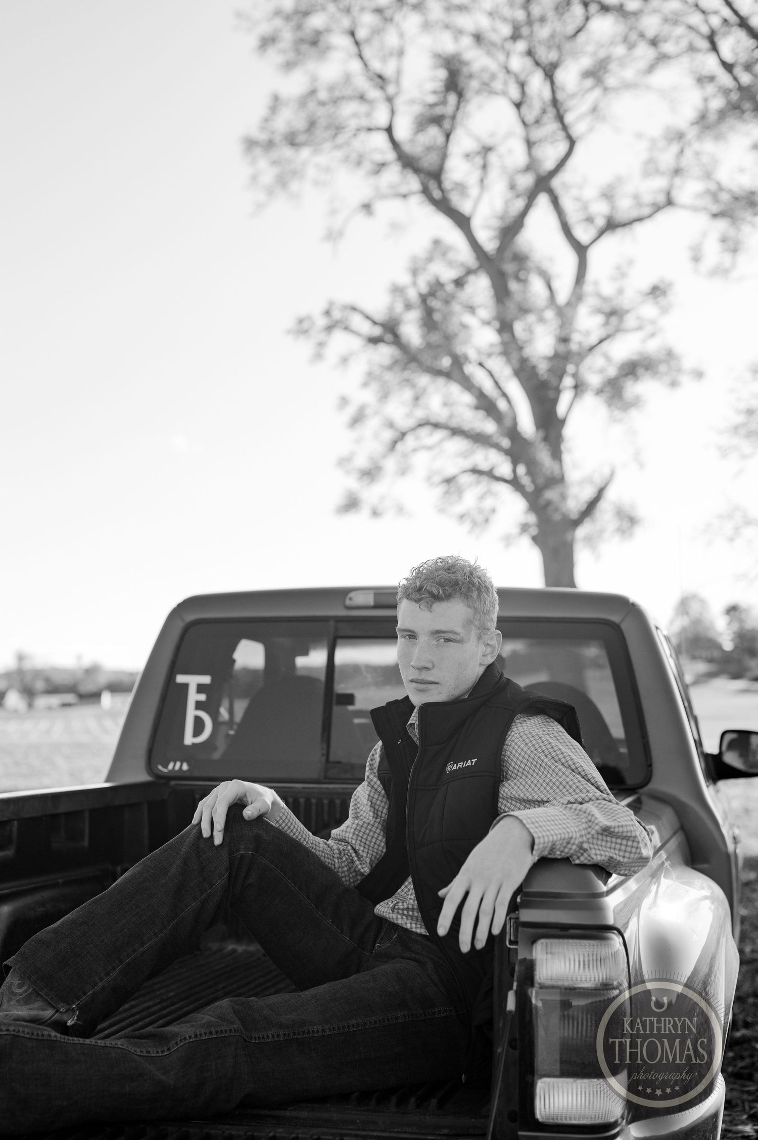 Black and white photo taken of someone sitting in truck bed.