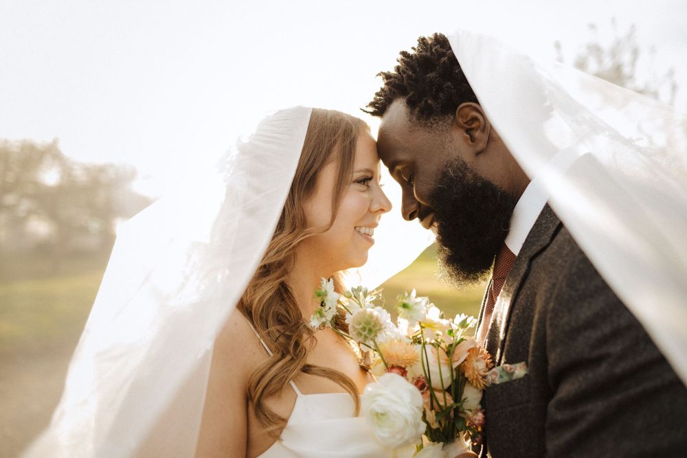 A bride and groom share an intimate moment under her veil during their outdoor sunset wedding ceremony near vernon nj.