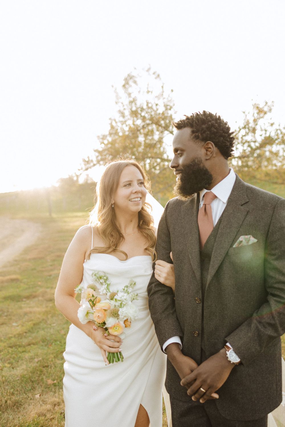 A couple shares a joyful moment at sunset during their outdoor wedding, with the bride holding a yellow bouquet near vernon nj.