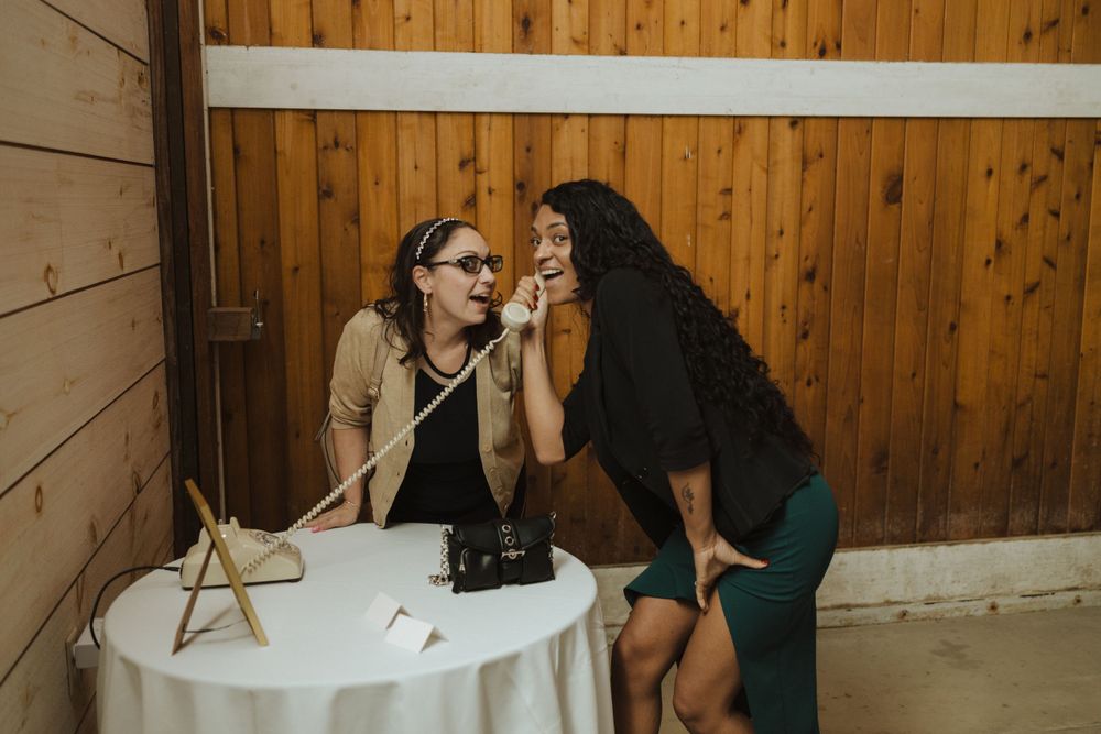 At a small white table against a wooden wall, two friends share an intimate conversation and moment together near vernon nj.