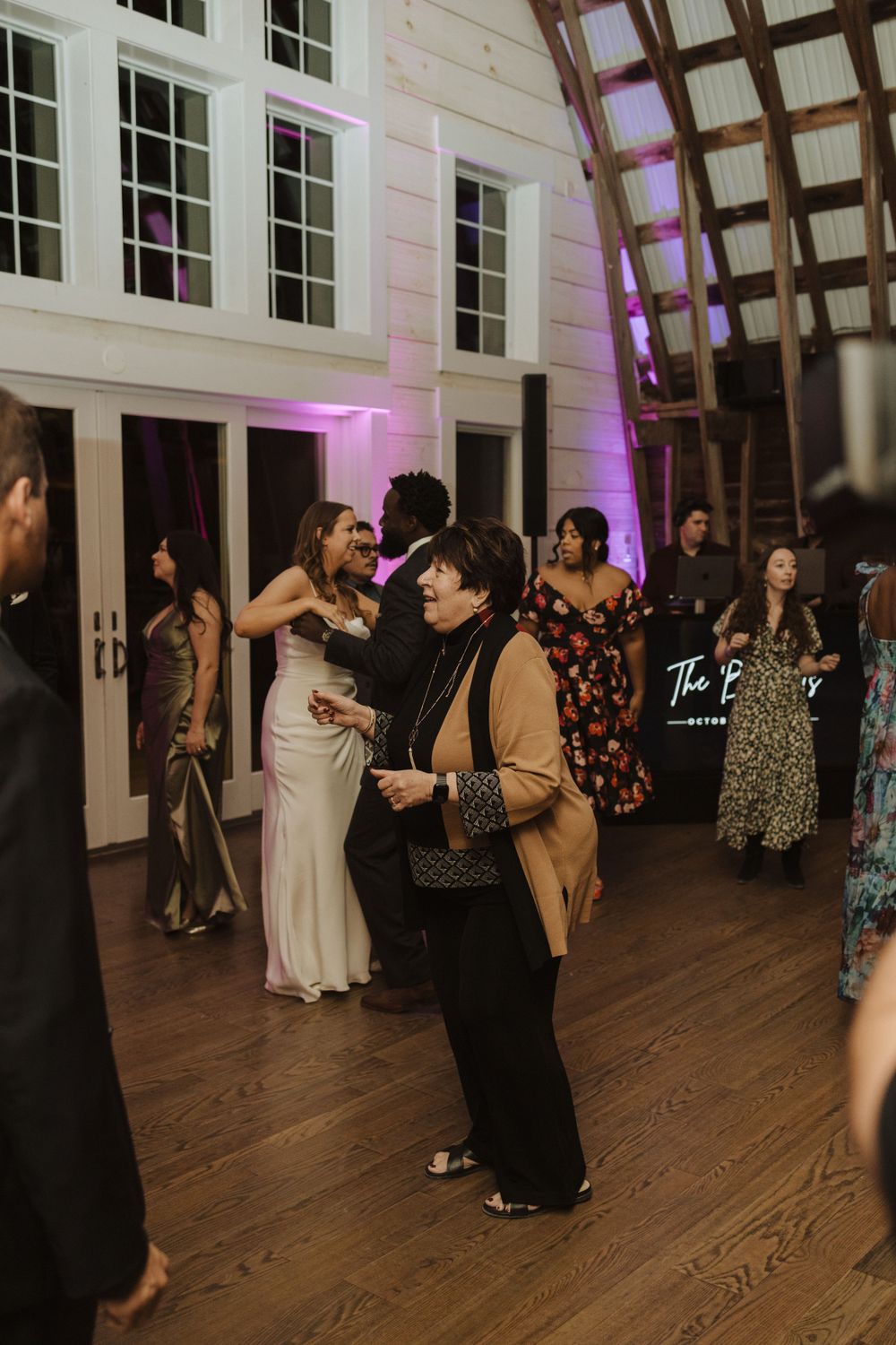Wedding guests dance and socialize in an elegant venue with high ceilings, wood floors, and purple accent lighting near vernon nj.