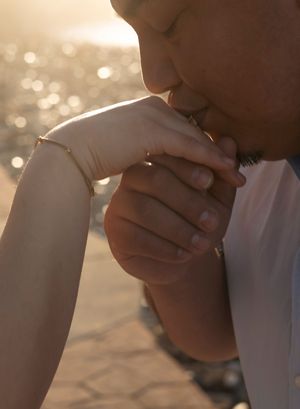 A tender romantic kissing moment captured in golden sunlight with bokeh effect in the background.