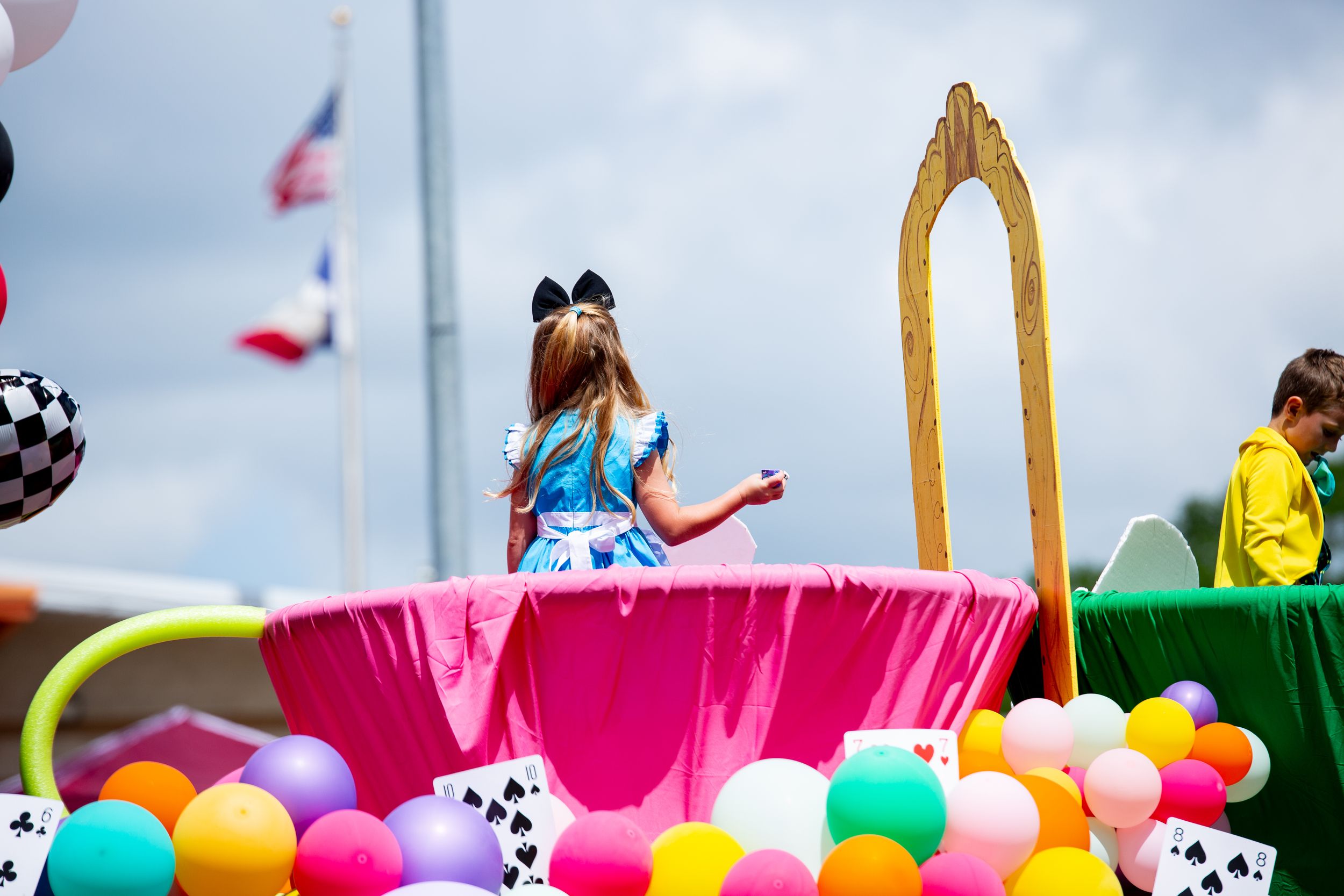 Colorful balloon arch display with pink, green, and yellow balloons against cloudy sky.