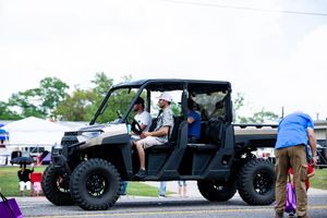 Military-style vehicles and utility trucks displayed at an outdoor community event.