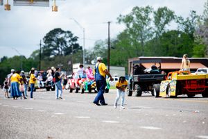 Crowd of spectators gathered outdoors watching an event in a parking lot area.
