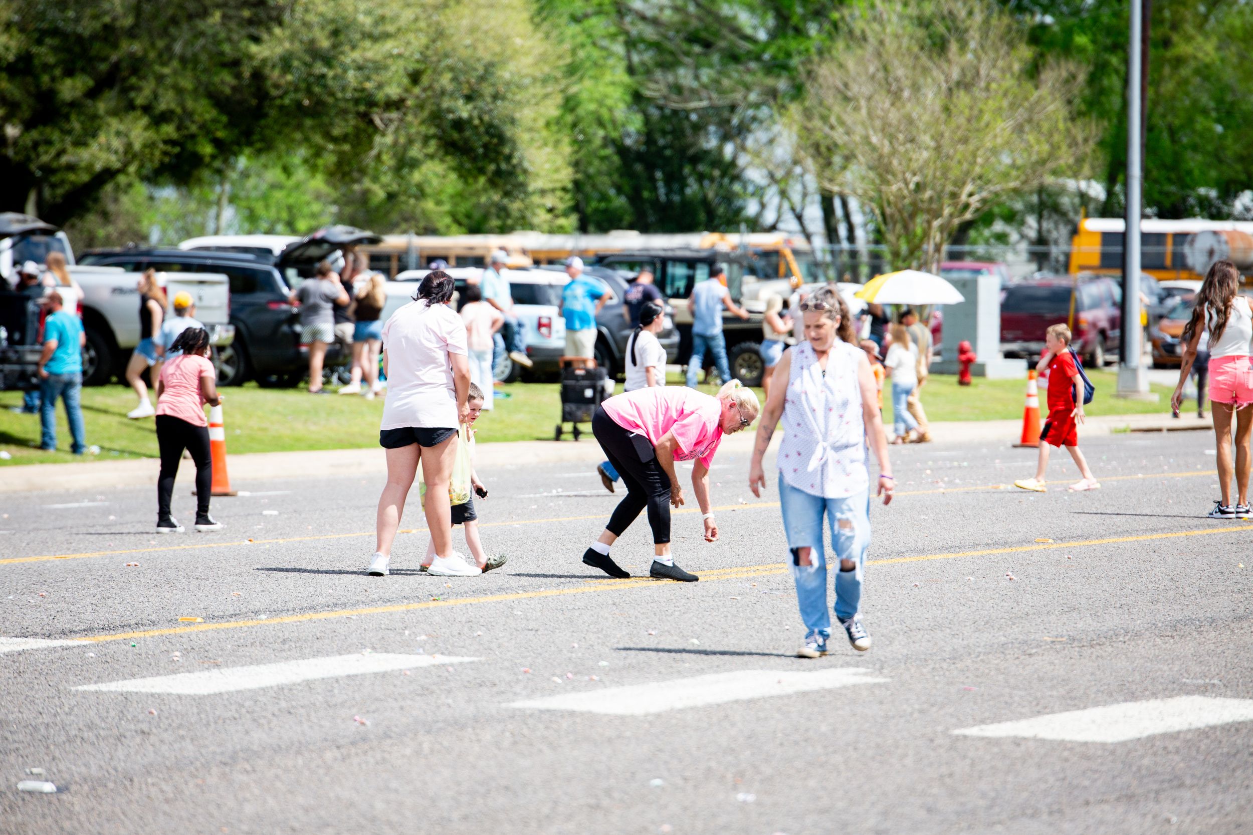 People walking and gathering in a parking lot during an outdoor community event.