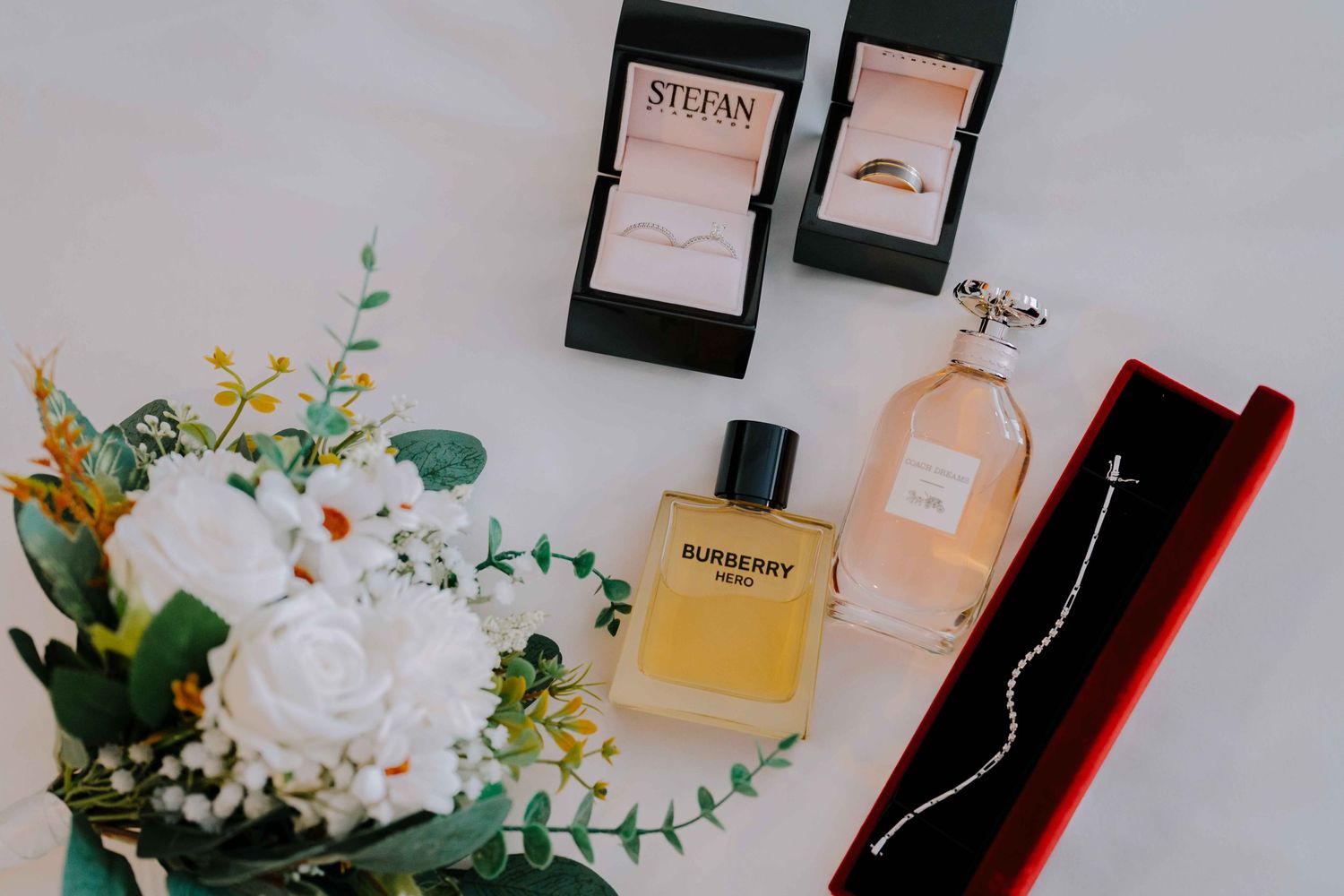 flatlay wedding perfume and wedding ring and floral bouquet