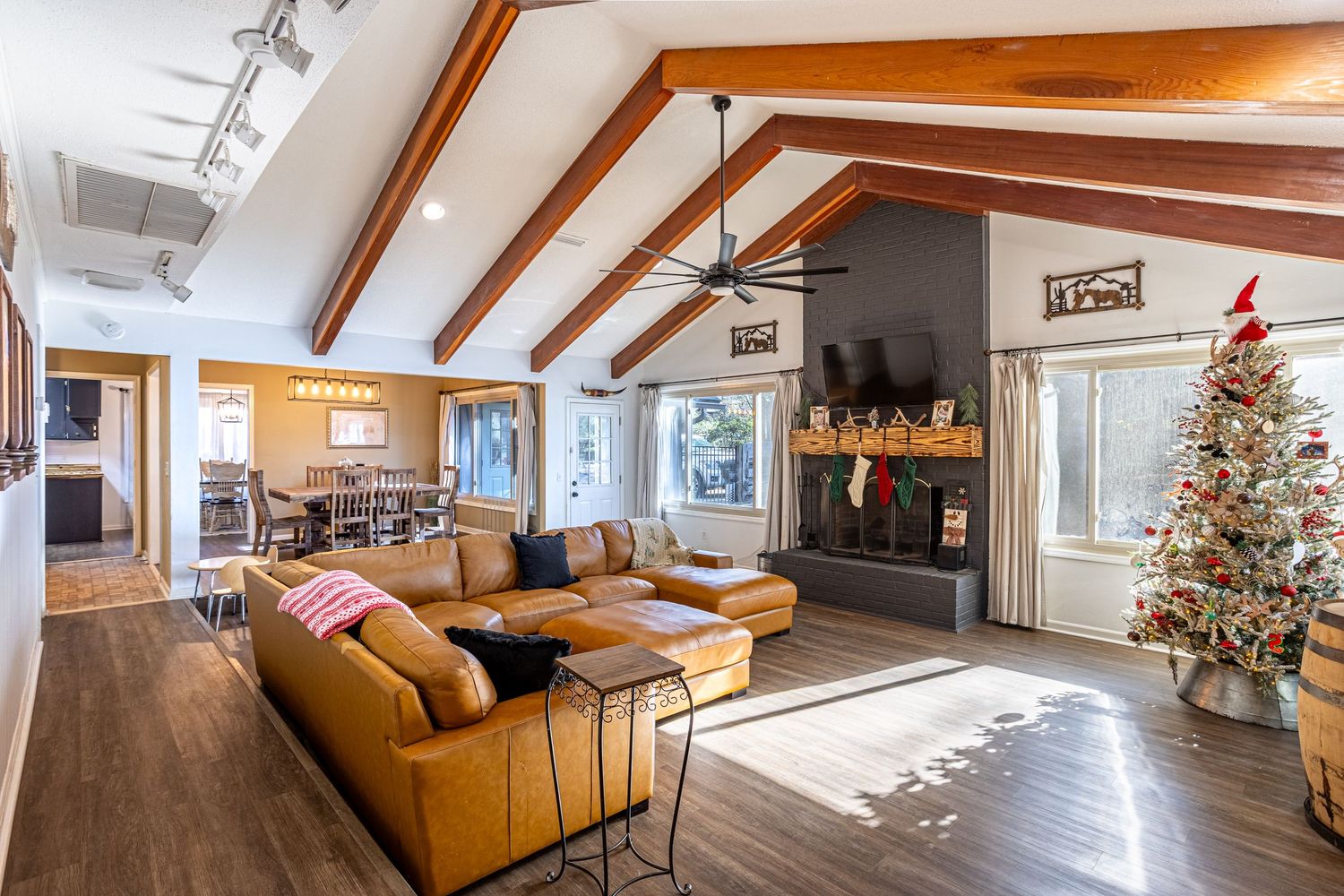 Modern open concept living room with vaulted ceiling, ceiling fan, neutral sectional sofa and connected kitchen space in Dothan, AL.