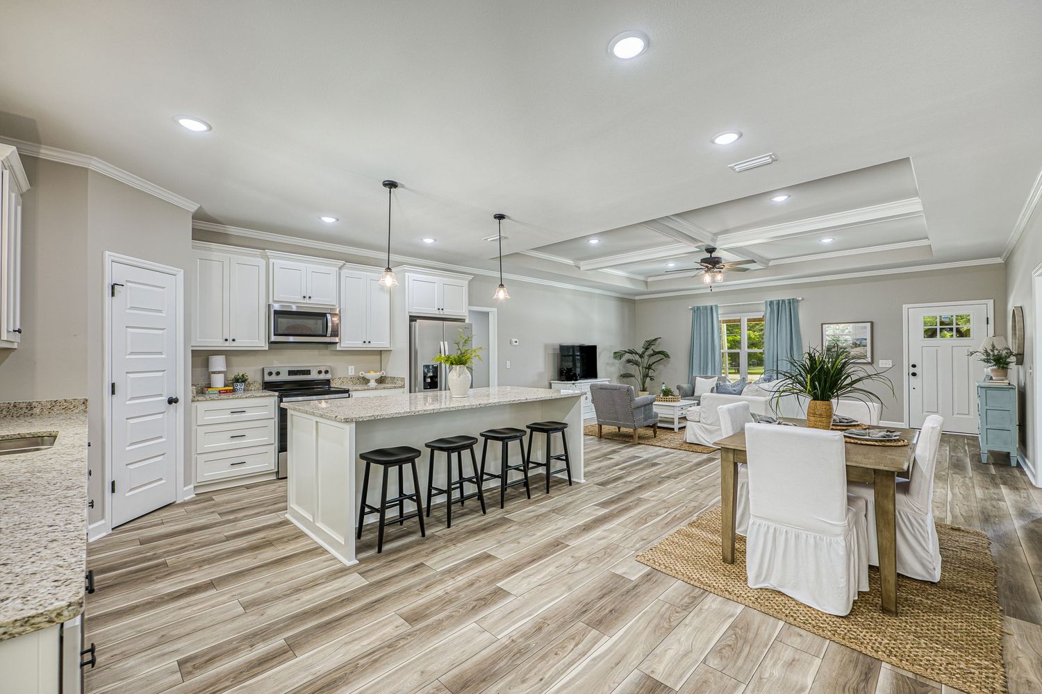 Modern open concept living room with vaulted ceiling, ceiling fan, neutral sectional sofa and connected kitchen space in Dothan, AL.