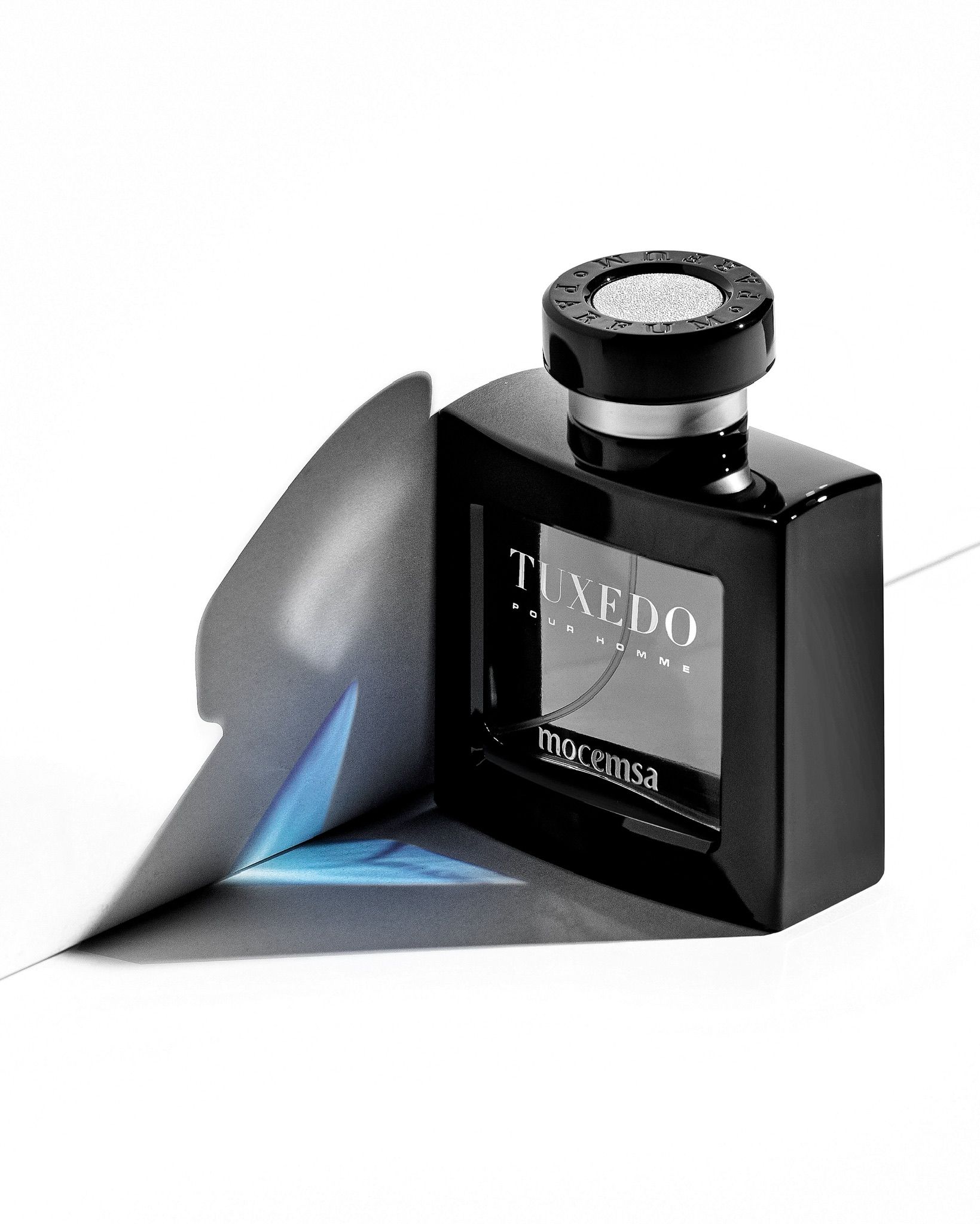 Sleek black Tuxedo Homme by Moccansa eau de parfum bottle with silver cap on white surface with blue light reflection.