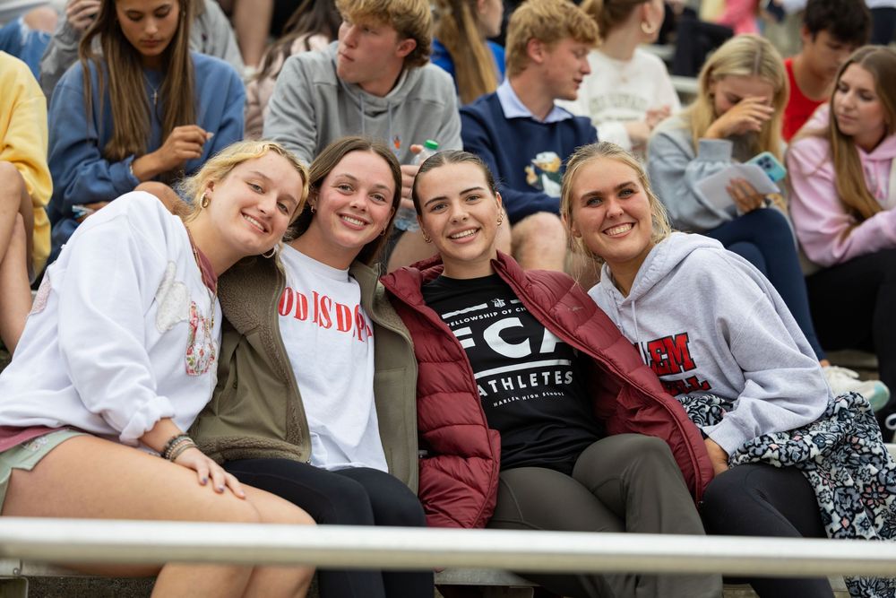 Students sit together in casual attire at a school event showing camaraderie and friendship.