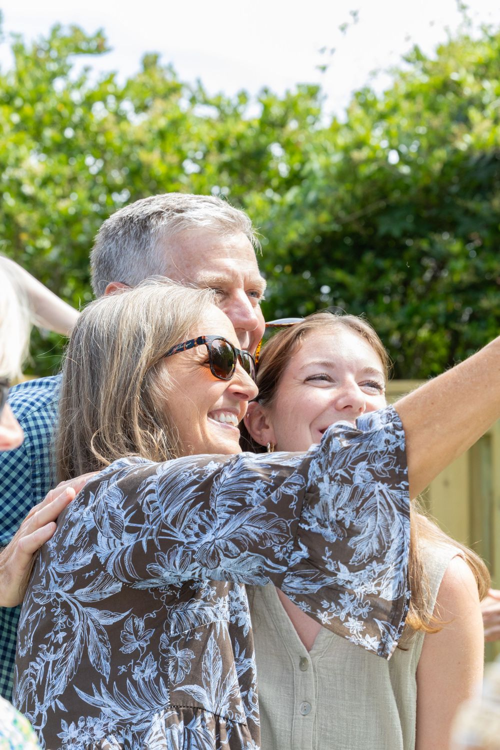 People dancing and having fun together at an outdoor party with green bushes in the background.