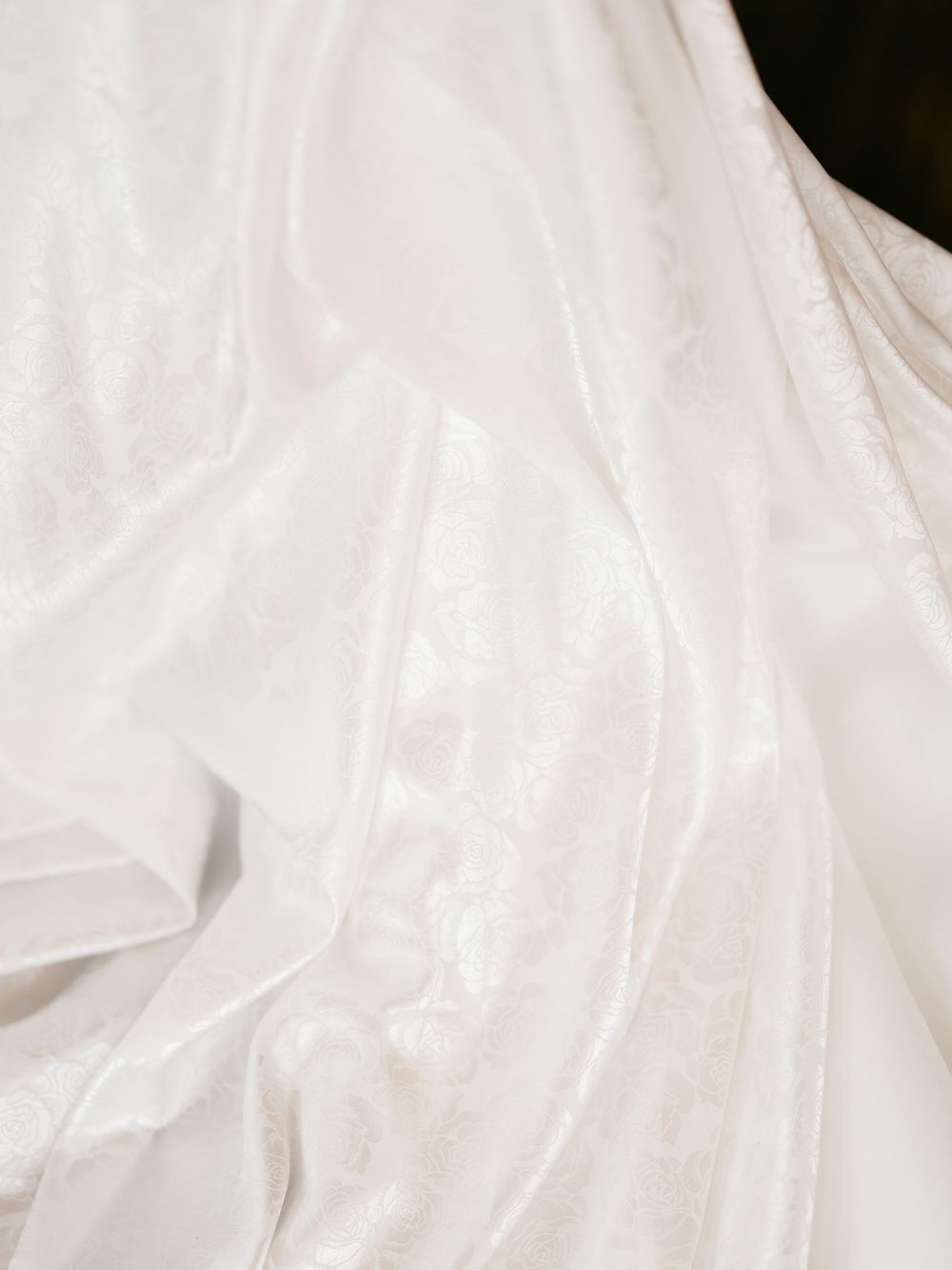 Flowing white wedding dress fabric creates elegant folds and texture in a classic bridal detail shot.