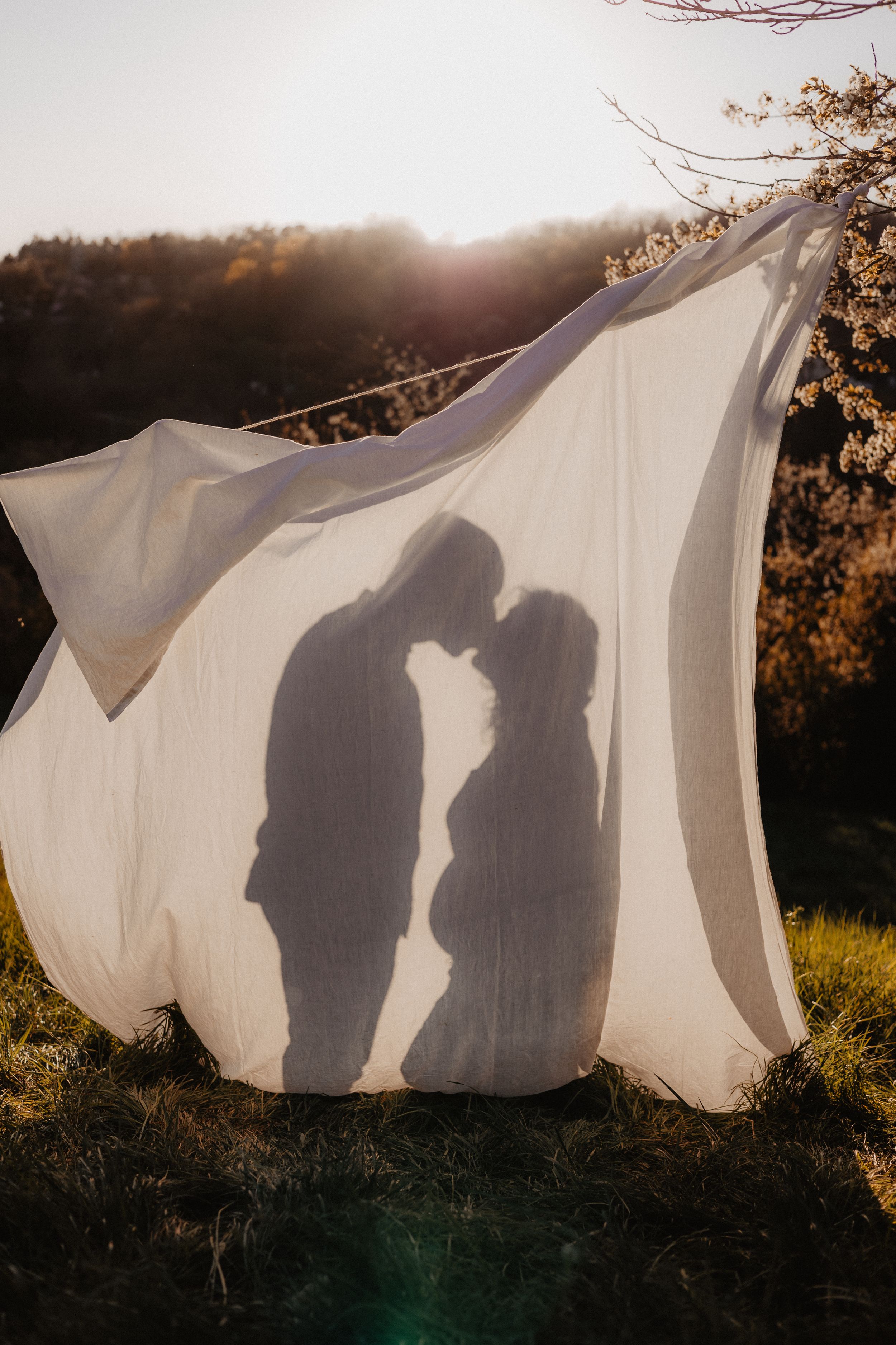Silhouettes behind flowing white sheets in golden sunset light.