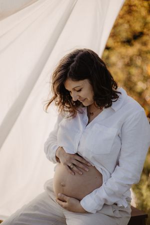 Ethereal maternity portraits in white clothing against natural outdoor backdrop.