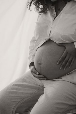 Close-up black and white maternity photos showing pregnant belly against white fabric.