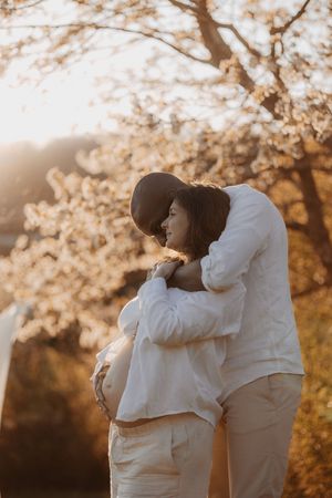Tender maternity photos at golden hour with couple in matching white outfits.