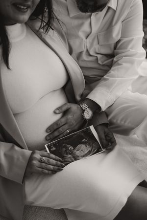 Couple looking at ultrasound photos together in intimate black and white photography.