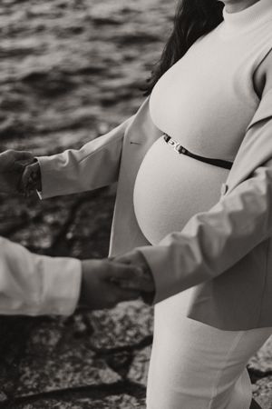 Black and white series of a pregnant figure in elegant white attire.